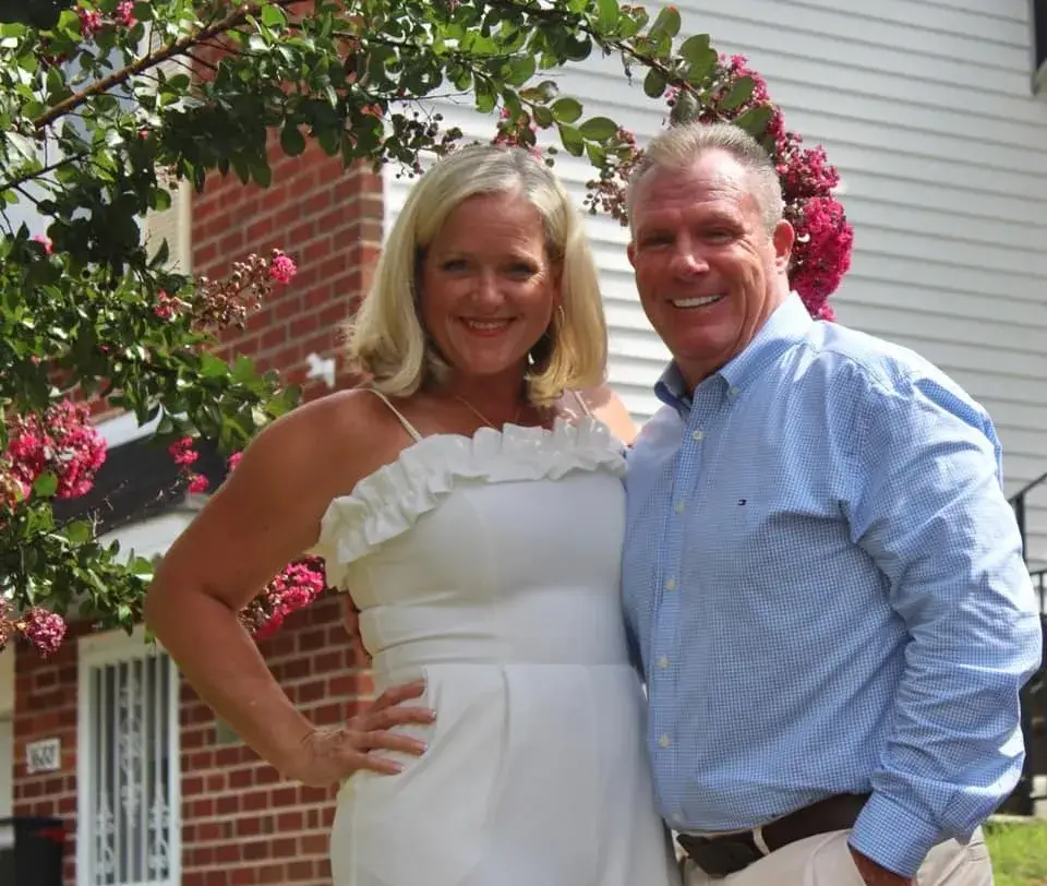 Smiling couple posing outside house with flowers