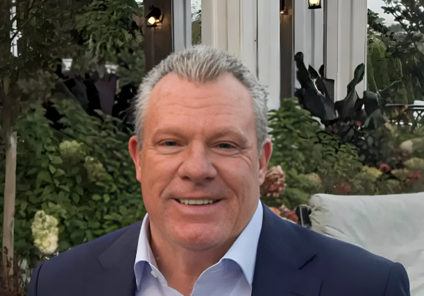 Smiling man in navy suit outdoors at patio