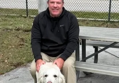 Man sitting with a dog on bench.