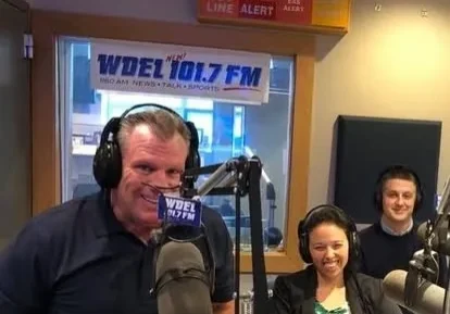 Radio hosts in a broadcast studio setting.