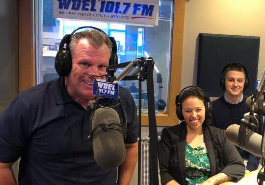 Three radio hosts smiling in WDEL studio