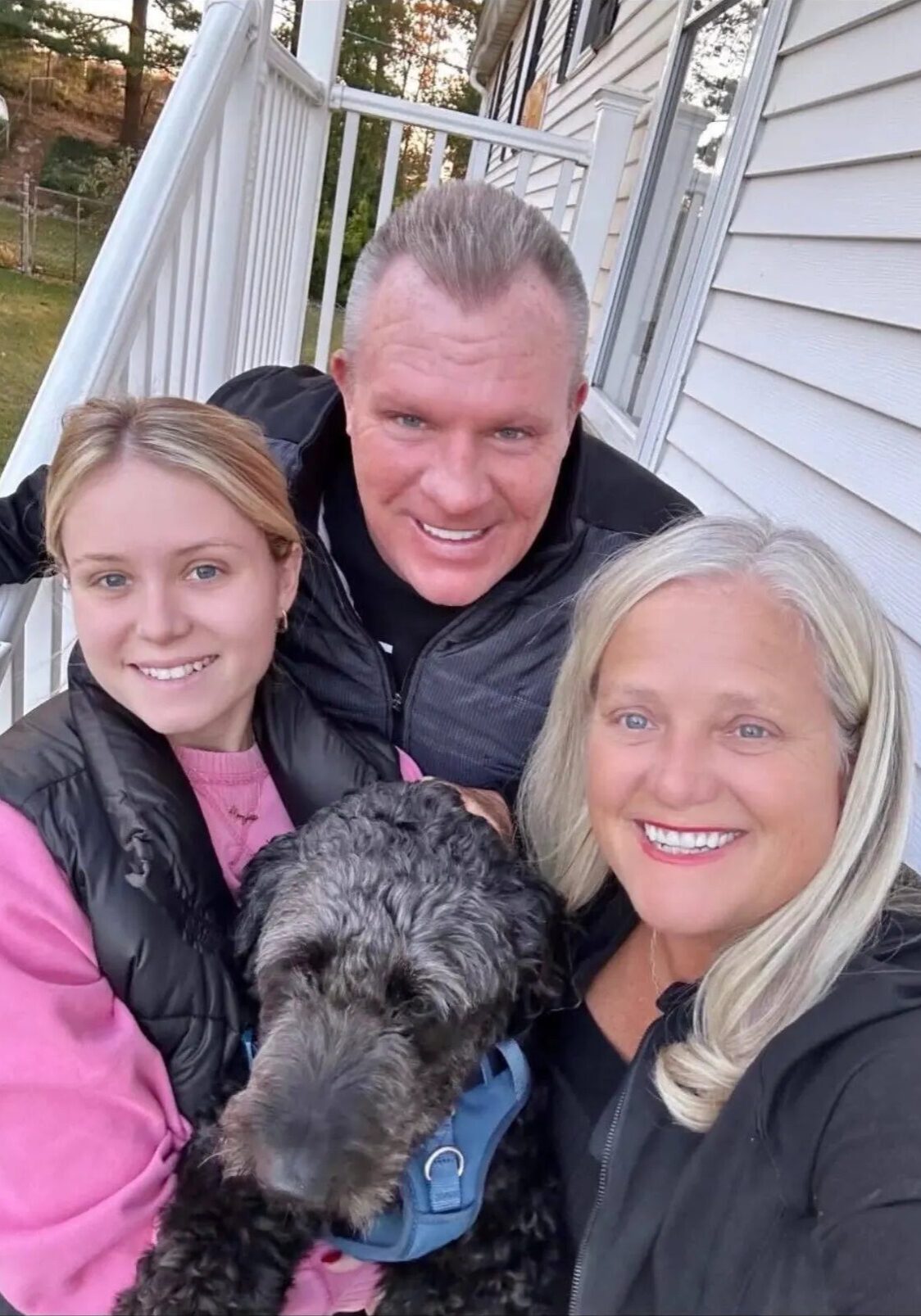 Porch selfie: three smiling people with dog