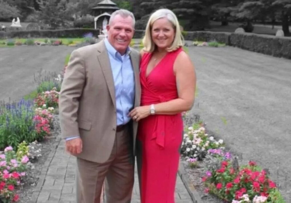 Couple posing in garden with colorful flowers.