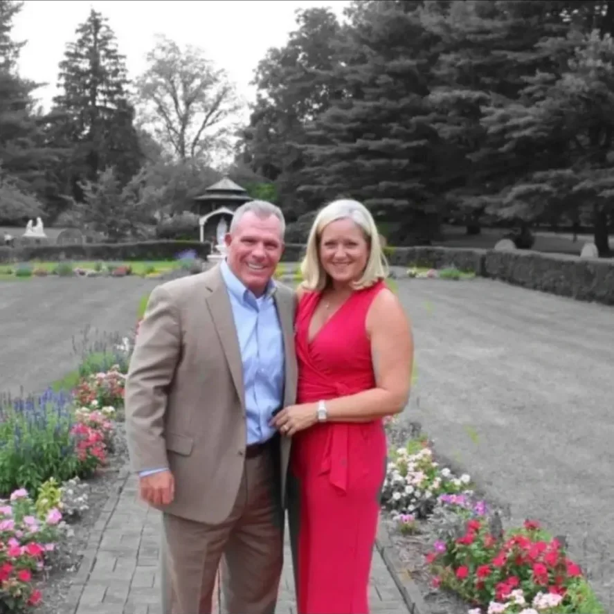 Couple smiling in formal attire amid garden